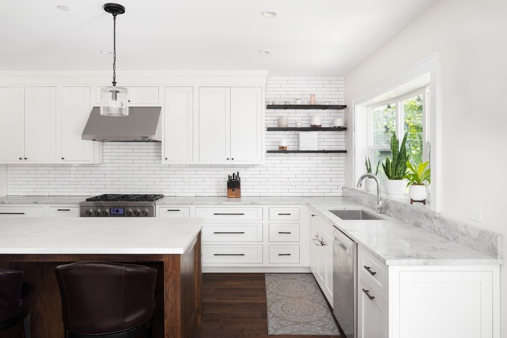 A beautiful modern farmhouse kitchen with white cabinets, large wood island and marble countertops