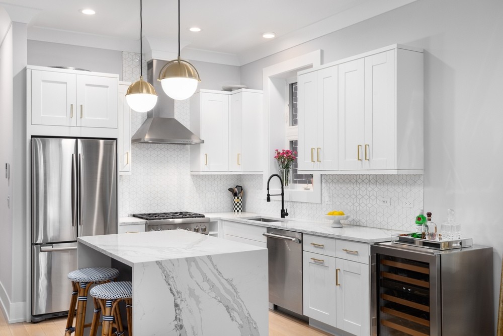 A beautiful white kitchen with bar stools sitting at a granite island