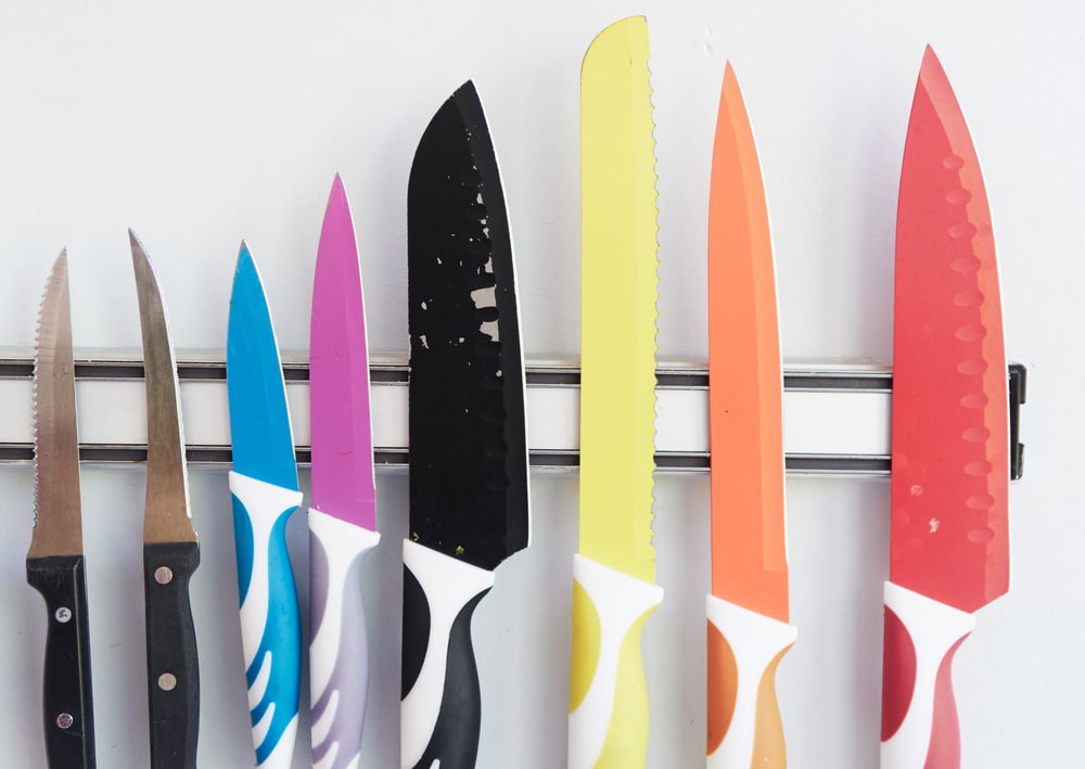 set of colorful kitchen knives on a magnetic strip on the tile wall