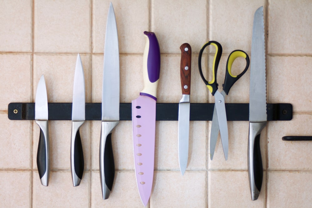 set of kitchen knives on a magnetic strip on the tile wall