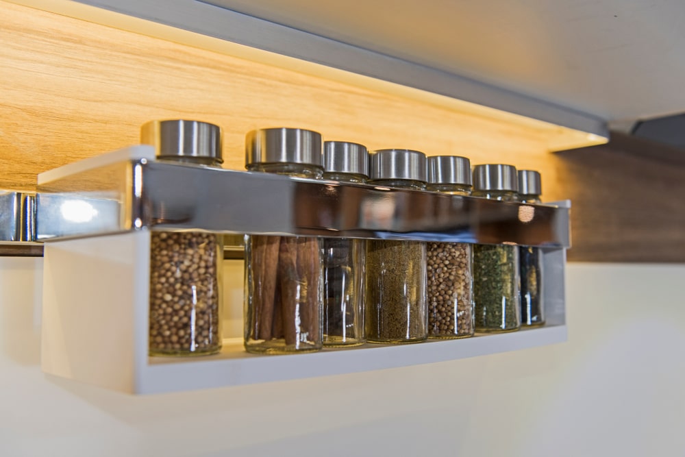 spice rack with glass jars in a row on wall