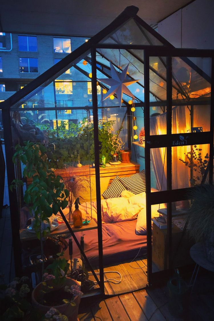 Glasshouse-style boho balcony glowing at night