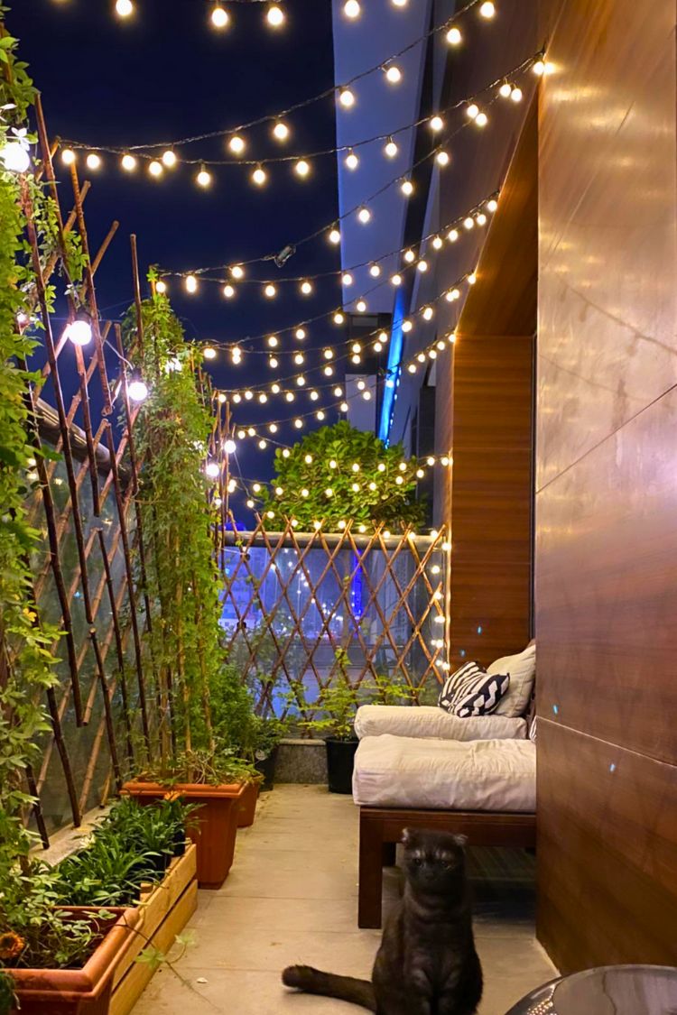 Intimate boho balcony with string lights and greenery