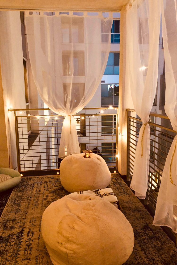 Soft boho balcony with draped curtains and poufs