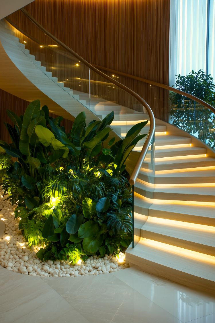 Modern under-stair garden with bold green plants and accent lighting