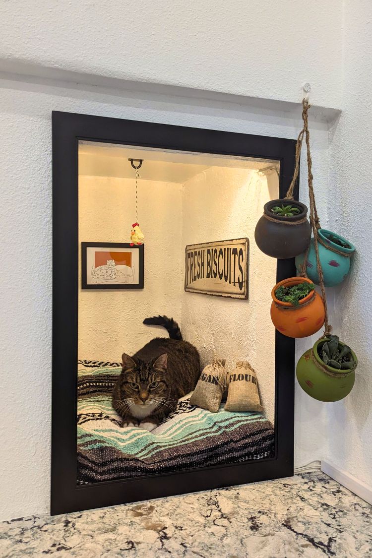 A small fireplace converted into a cozy nook with a cushion and hanging mugs on the side